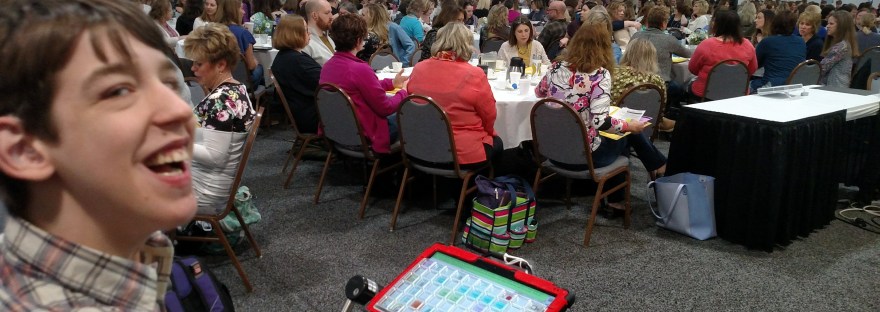 Justin smiling with audience seated at tables in background