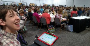 Justin smiling with audience seated at tables in background