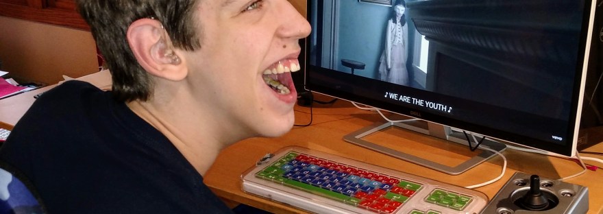 Justin smiling at computer monitor with captioned video