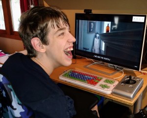 Justin smiling at computer monitor with captioned video