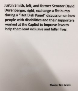 Plaque describing picture: "Justin Smith, left, and former Senator David Durenberger, right, exchange a fist bump during a "Hot Dish Panel" discussion on how people with disabilities and their supporters worked at the Capitol to improve laws to help them lead inclusive and fuller lives. Photo: Tim Lewis"