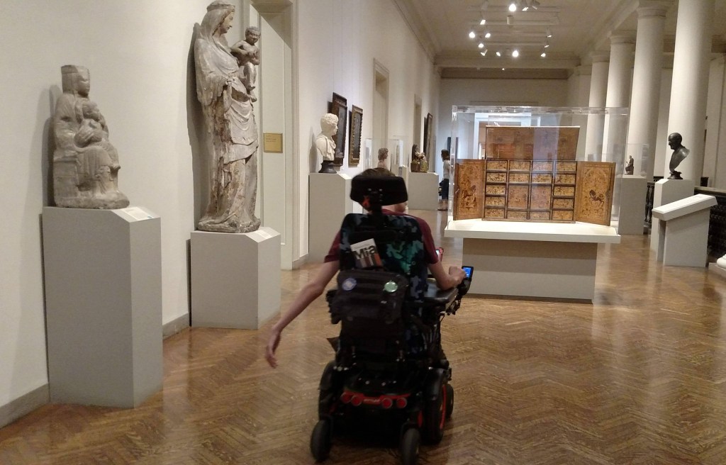 Justin driving wheelchair in art institute hallway with statues