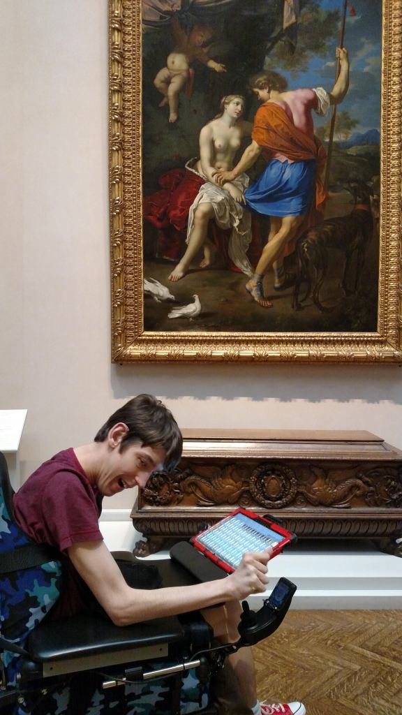 Justin driving his wheelchair in front of painting