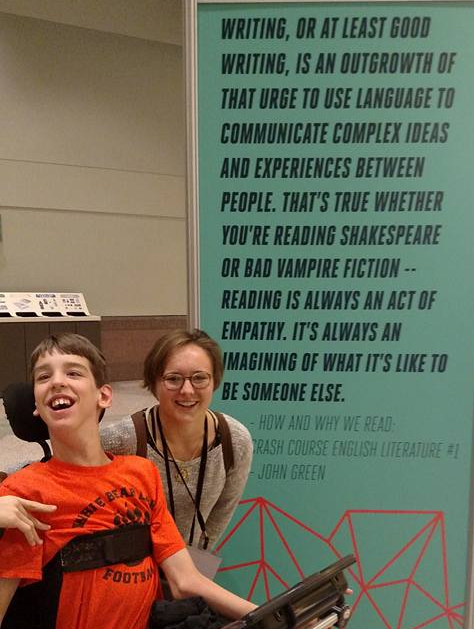 Justin and Annie in front of poster with John Green quote