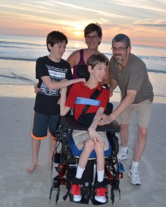 Justin, younger brother, mom and dad smiling on sandy ocean beach