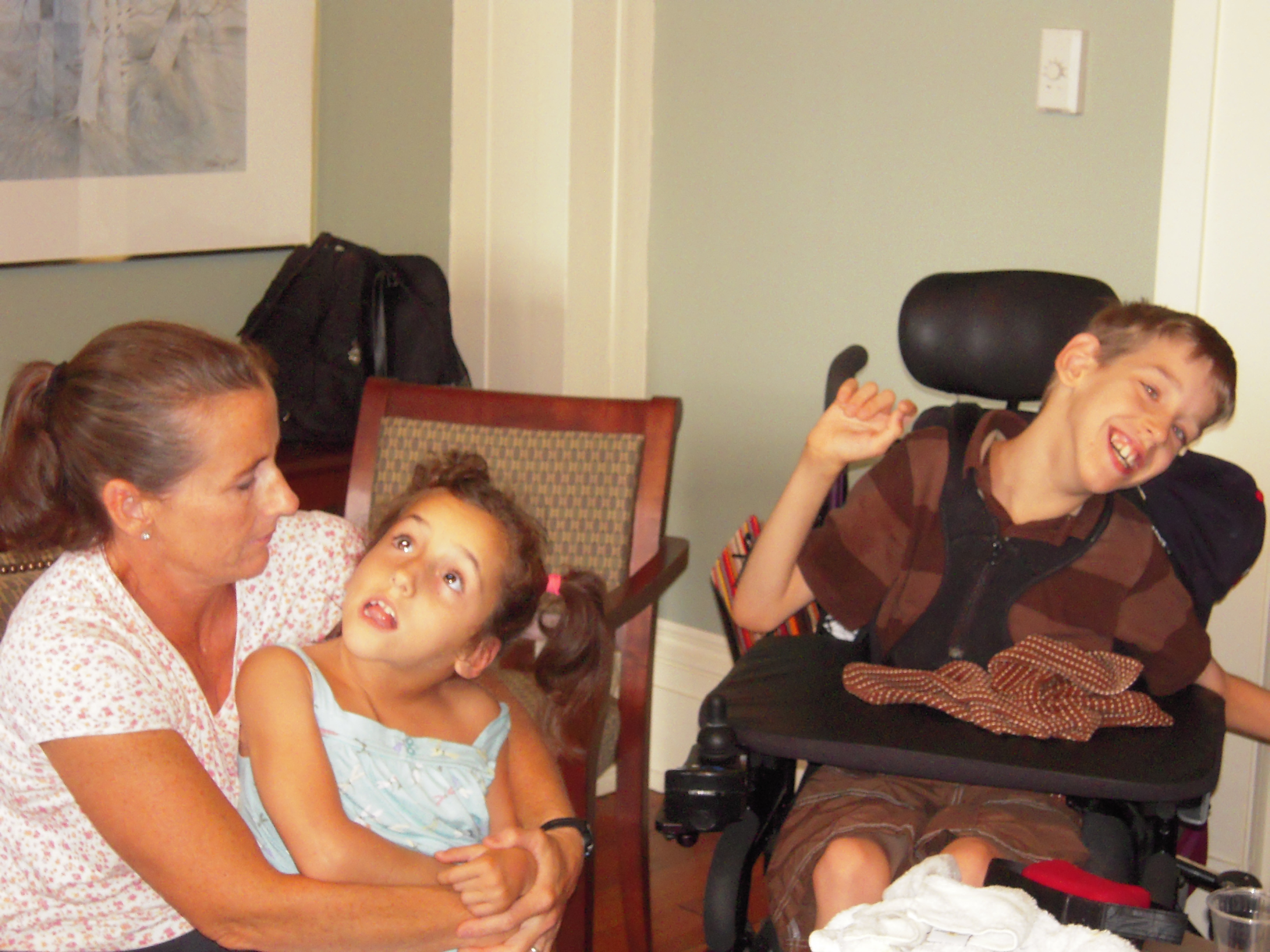 Lexi held by her mom, Justin smiling in his wheelchair