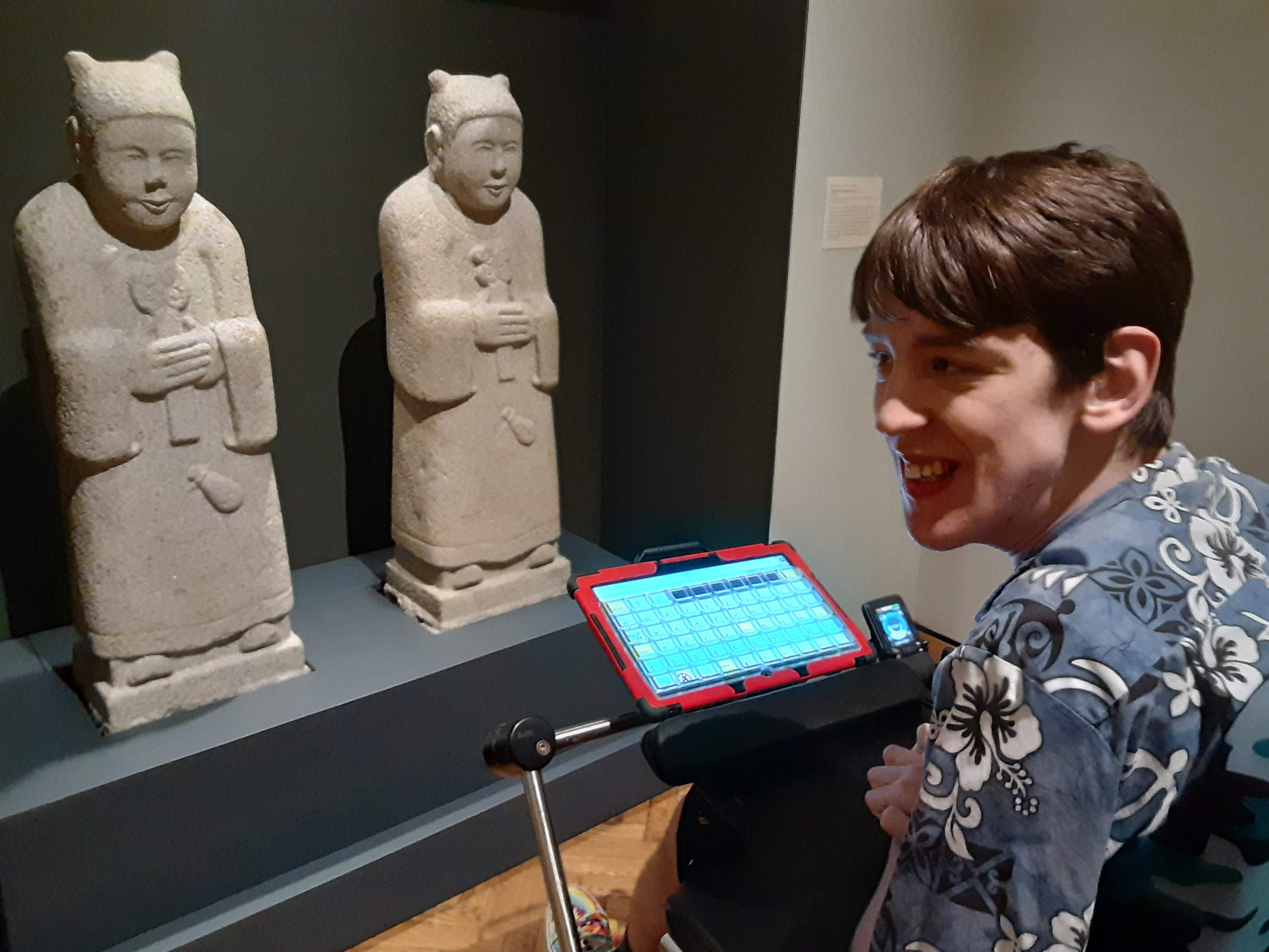 Justin in wheelchair looking at Korean Tomb guardian figures