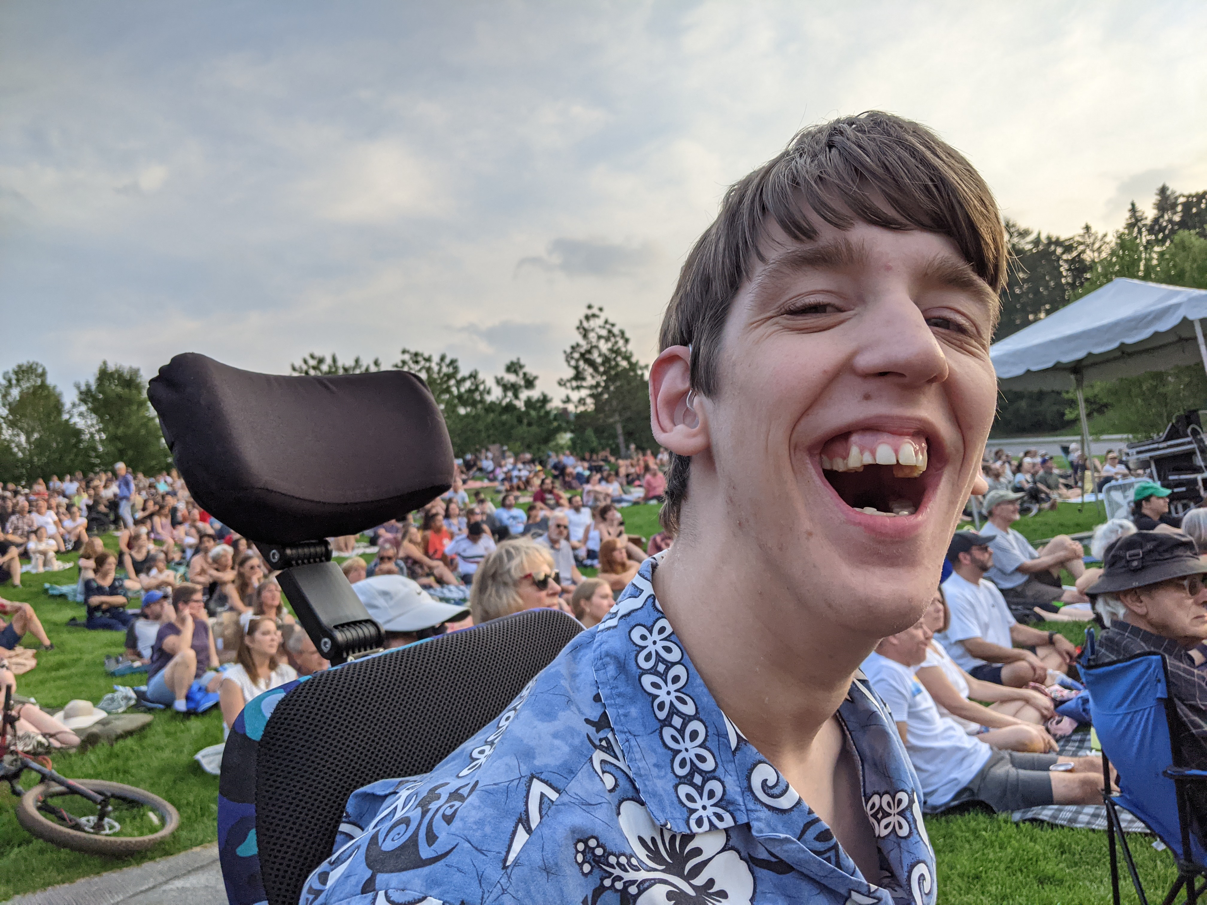 Justin in wheelchair, laughing, hillside behind filled with people watching jazz concert