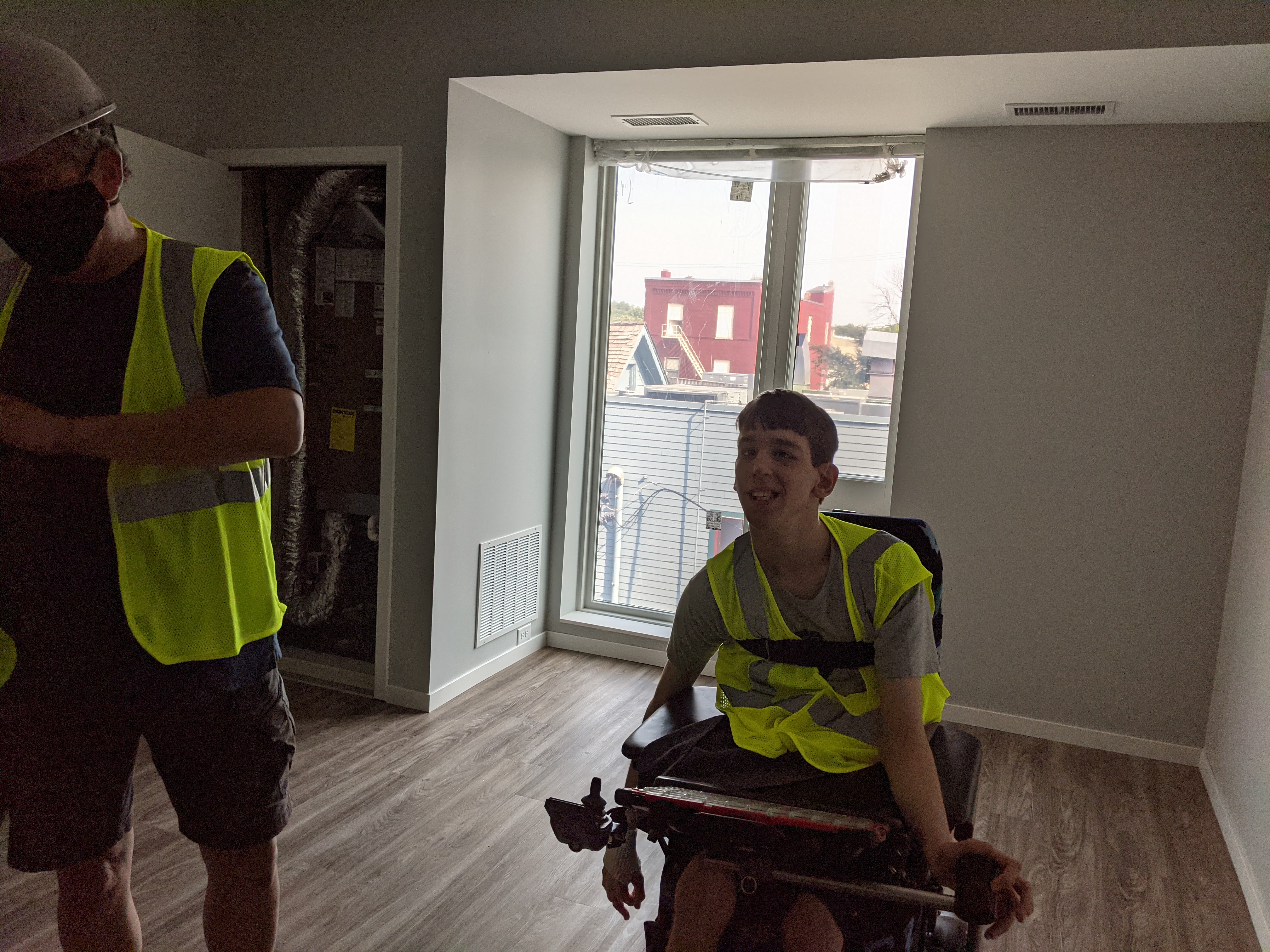Justin smiling, Dad with vest and helmet, empty living room