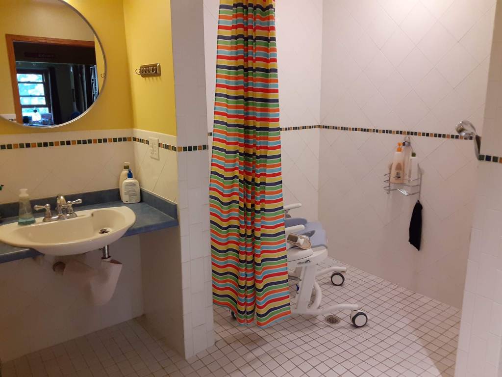 Roll in shower with adaptive shower chair and roll-under sink