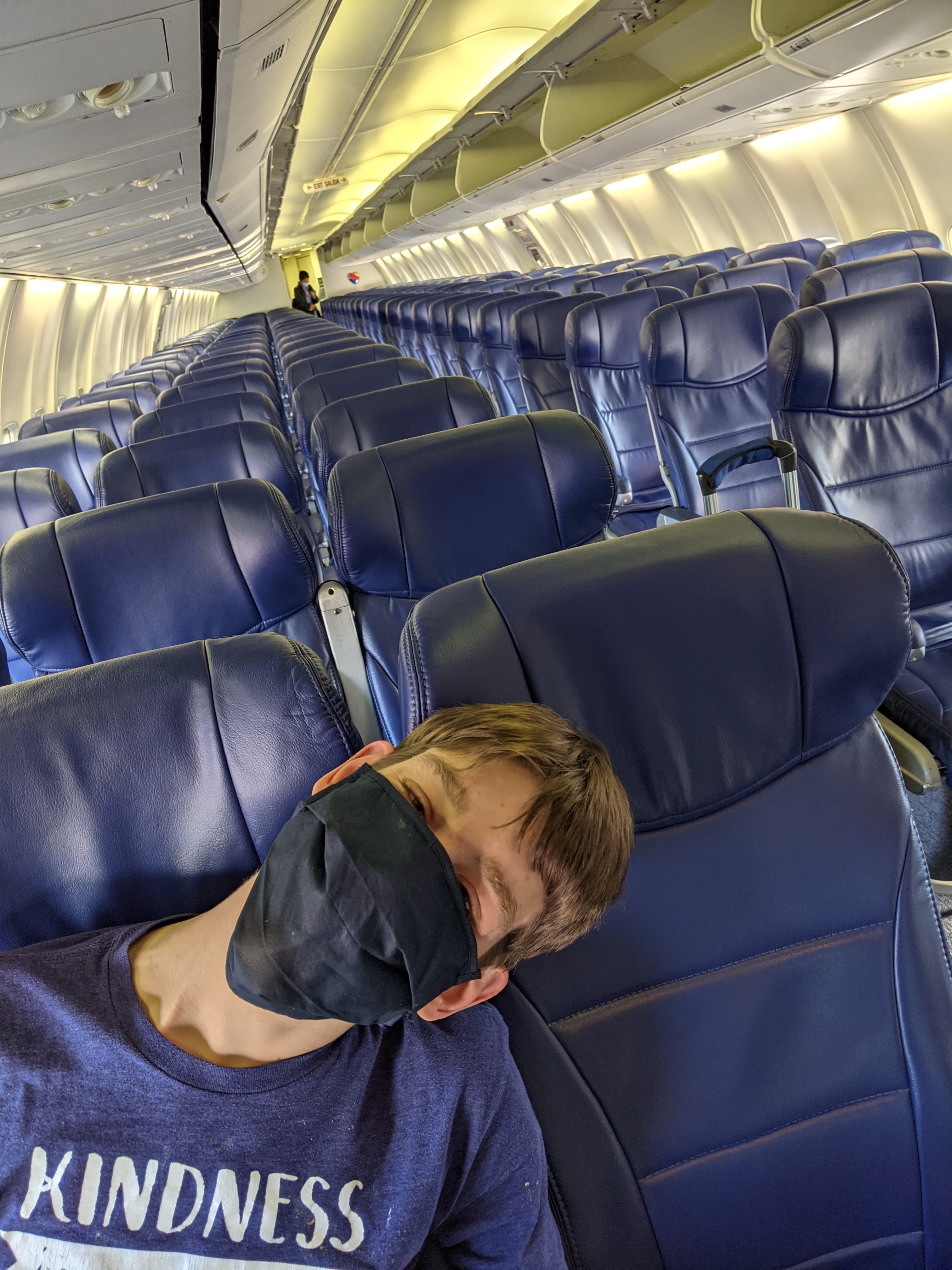 23-year old Justin, wearing mask, sitting in airplane seat in empty airplane