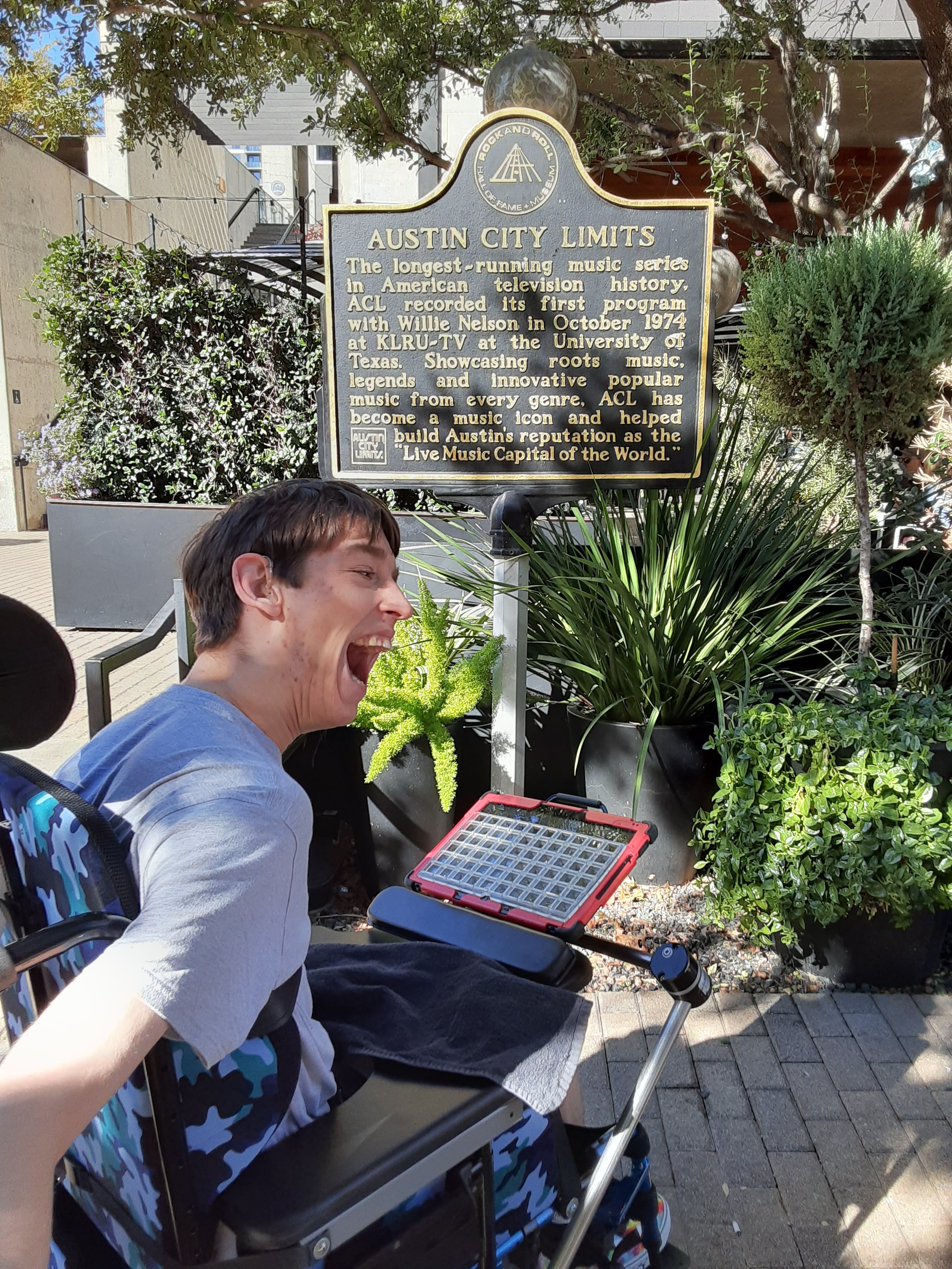 Justin in wheelchair in front of Austin City Limits historical sign