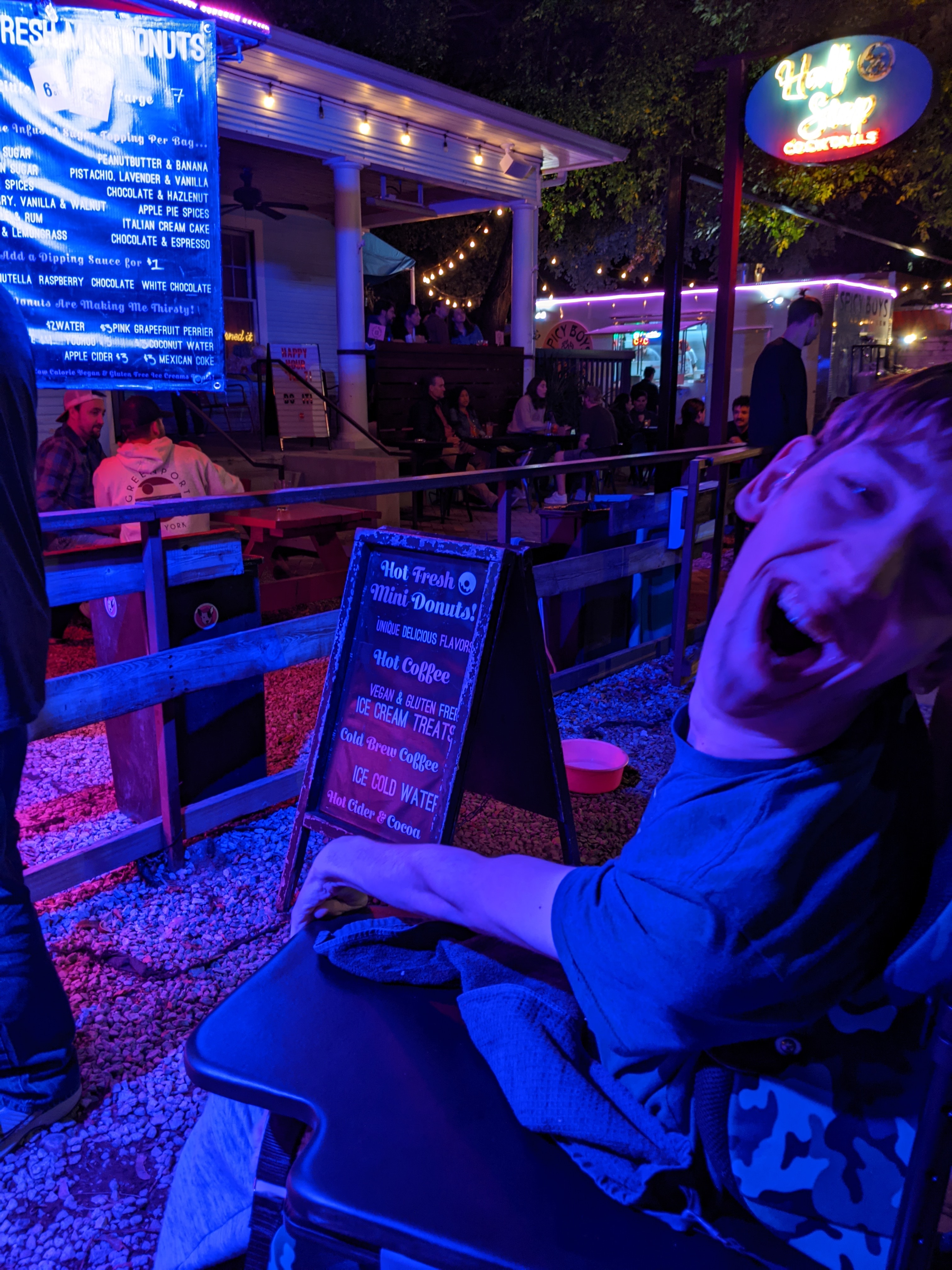 Justin laughing, in front of donut food truck on Rainey Street at night