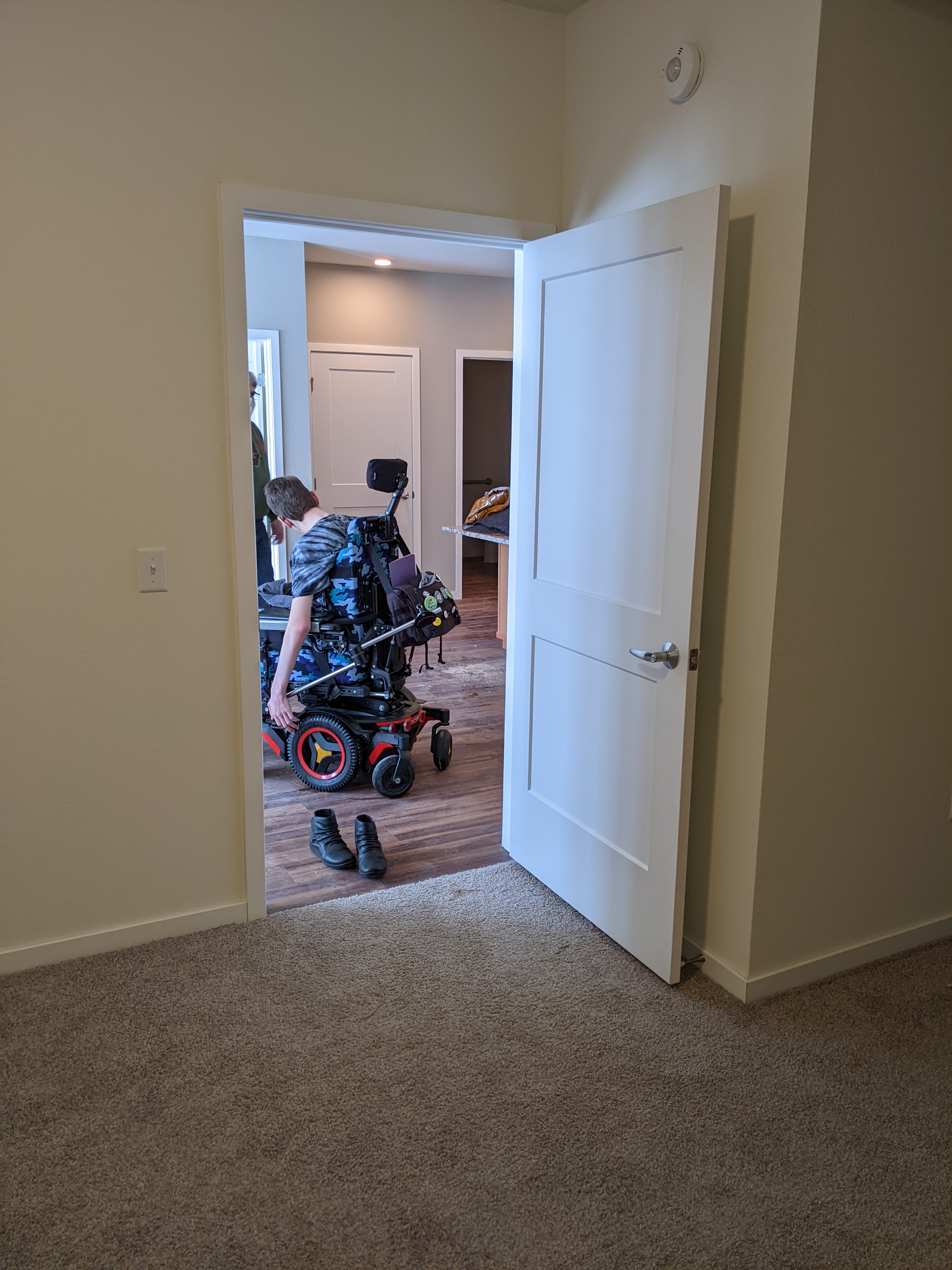Back of Justin in wheelchair in living room taken from carpeted bedroom
