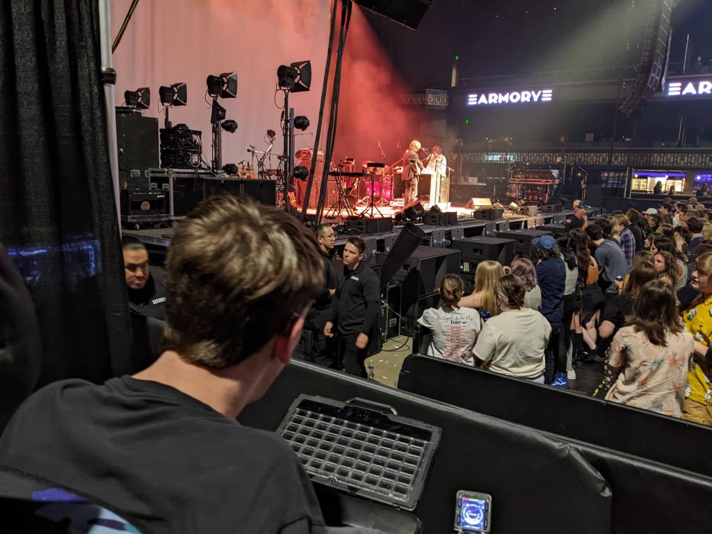 Justin looking at band on stage, crowd of people below him