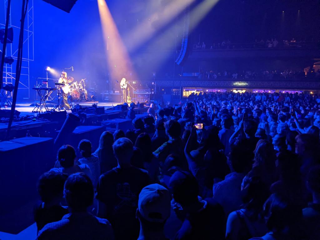 HAIM band on stage, purple lighting, crowd