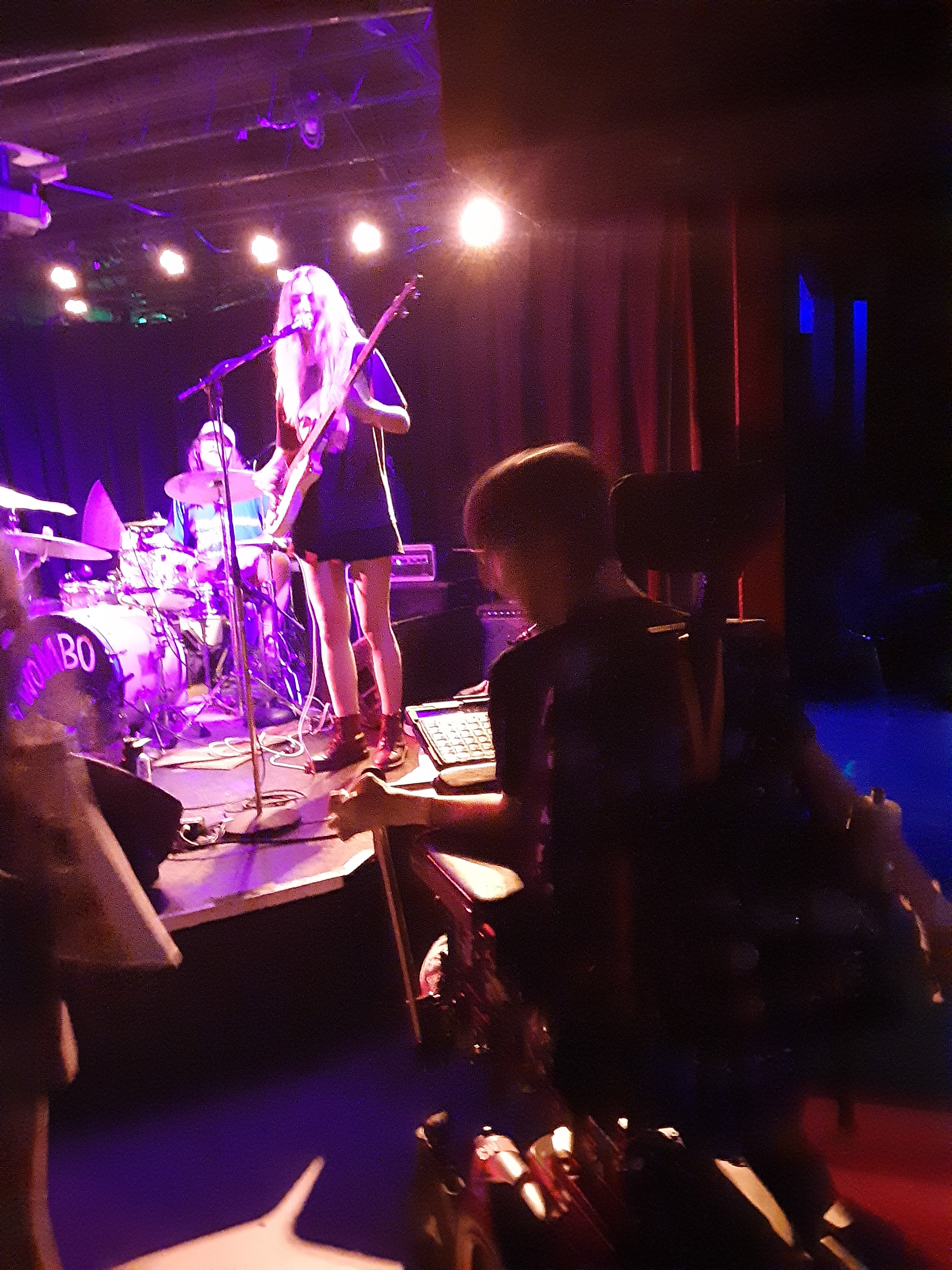 Blurry image of Justin in raised wheelchair watching Wombo band playing on 7th street entry stage
