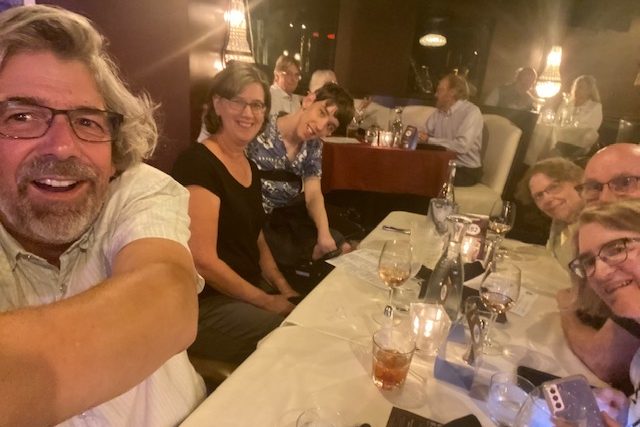 Justin seated in wheelchair at white tablecloth table with his parents, grandma, aunt and uncle