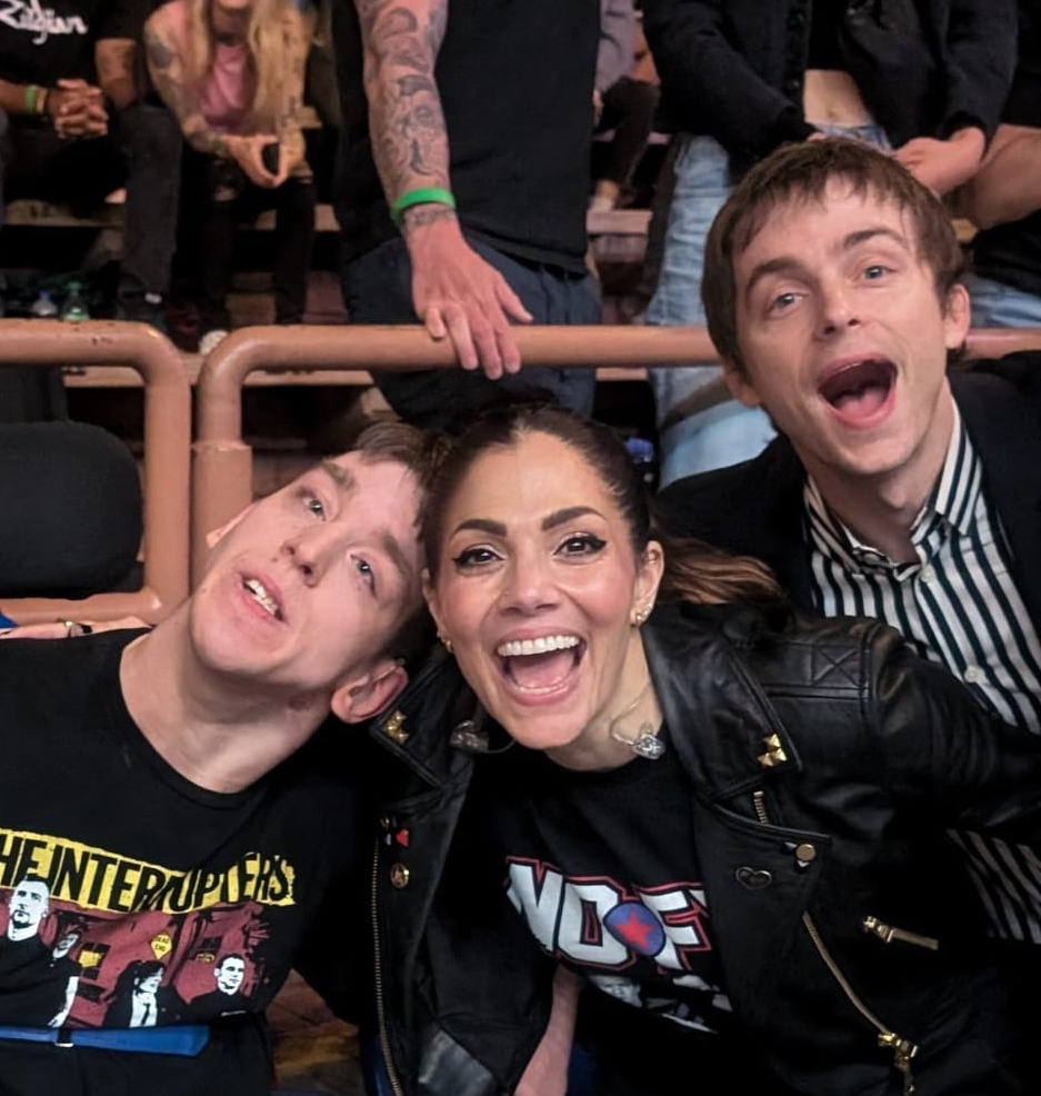 Justin, young man in wheelchair with lead singer and guitarist from Interrupters, concert goers behind them