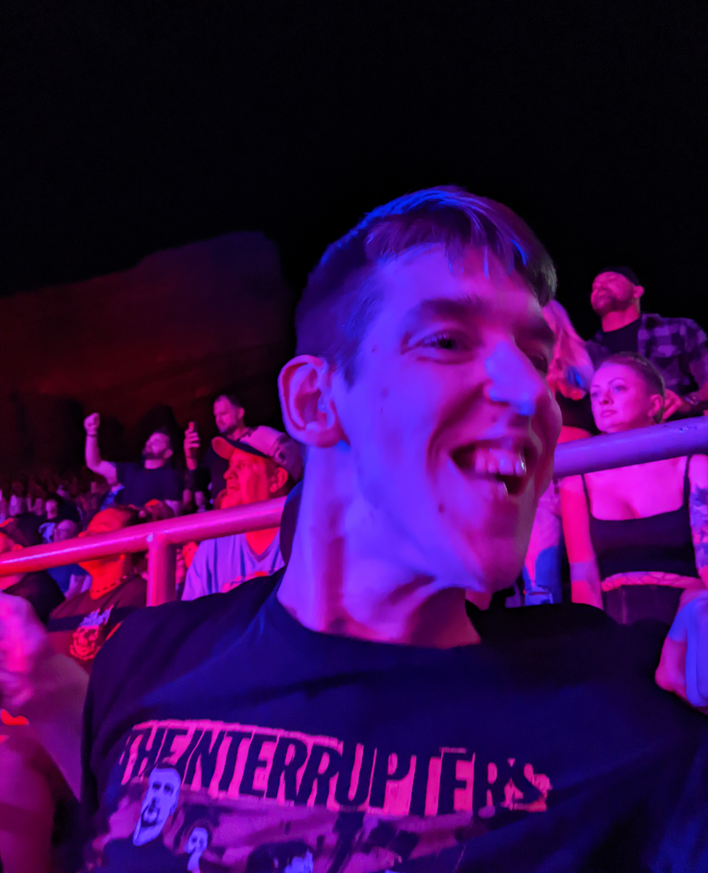 Justin smiling, crowd behind, purplish glow from stage lights