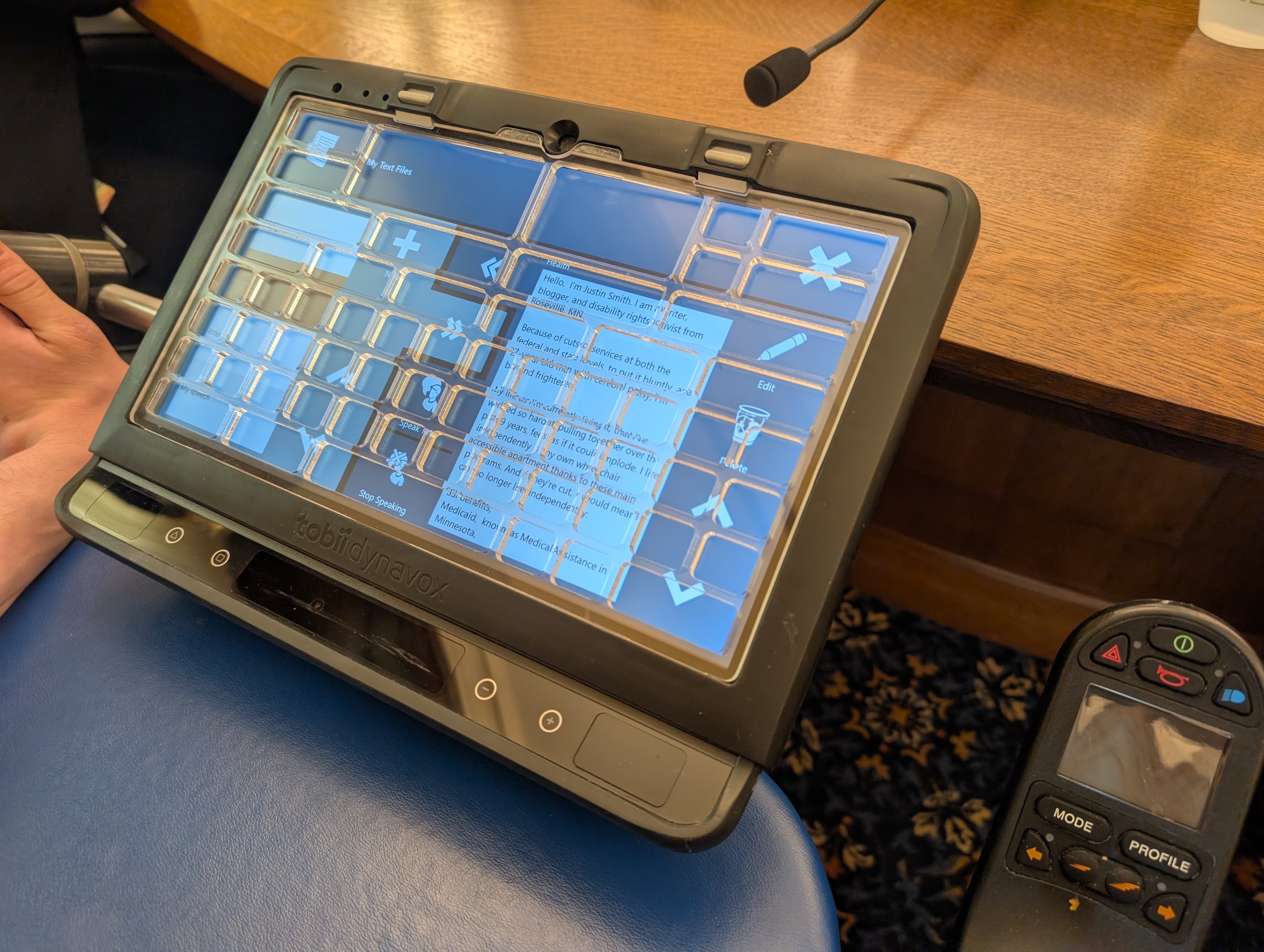 Communication device resting on the wheelchair tray, microphone in front of it