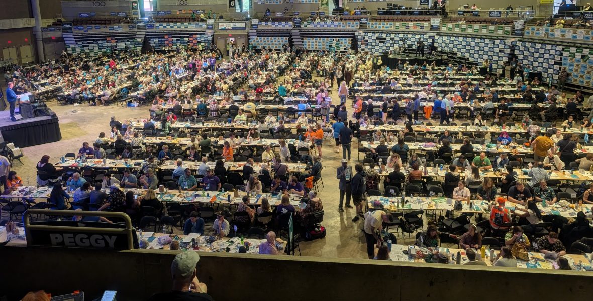 Looking down at the crowded convention floor filled with tables, people, stage with podium